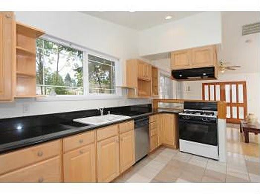Modern kitchen with wooden cabinets and black countertops.