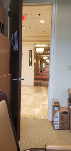 A view of a hotel lobby through an open doorway, featuring elegant chandeliers and polished floors.