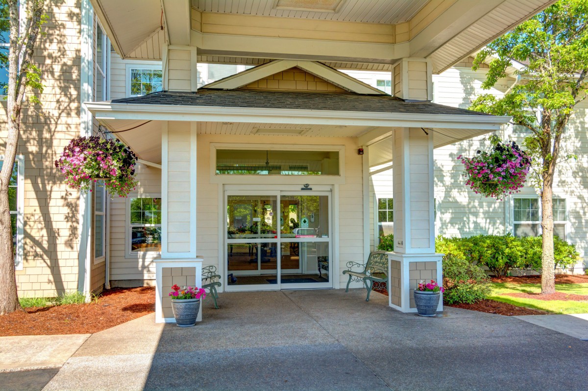 A welcoming entrance to a building with an awning and decorative plants.