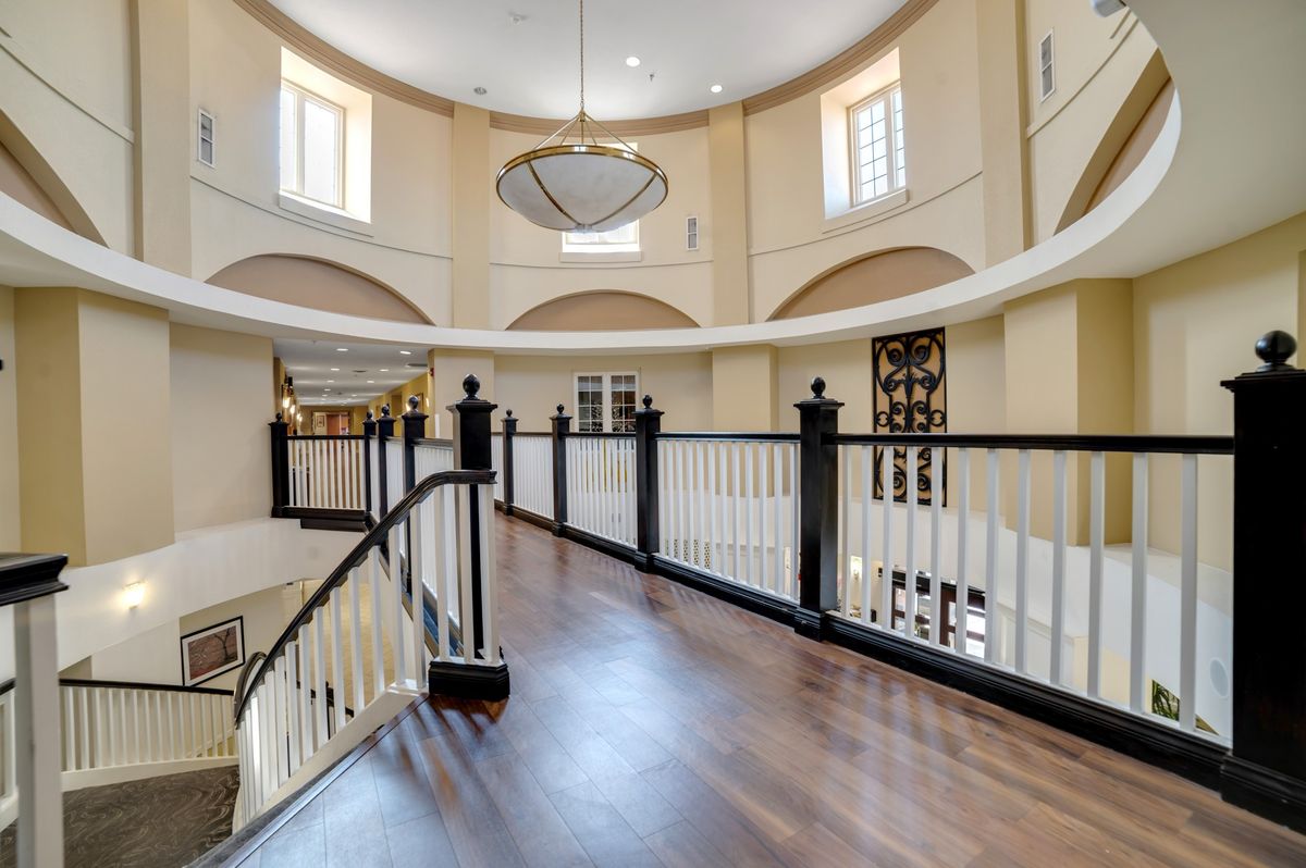 Elegant interior with a wooden floor, curved balcony, and a large chandelier.