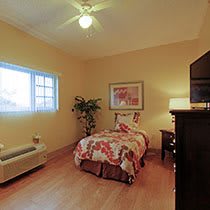 A cozy bedroom with a single bed, decorated with warm tones and a large window.