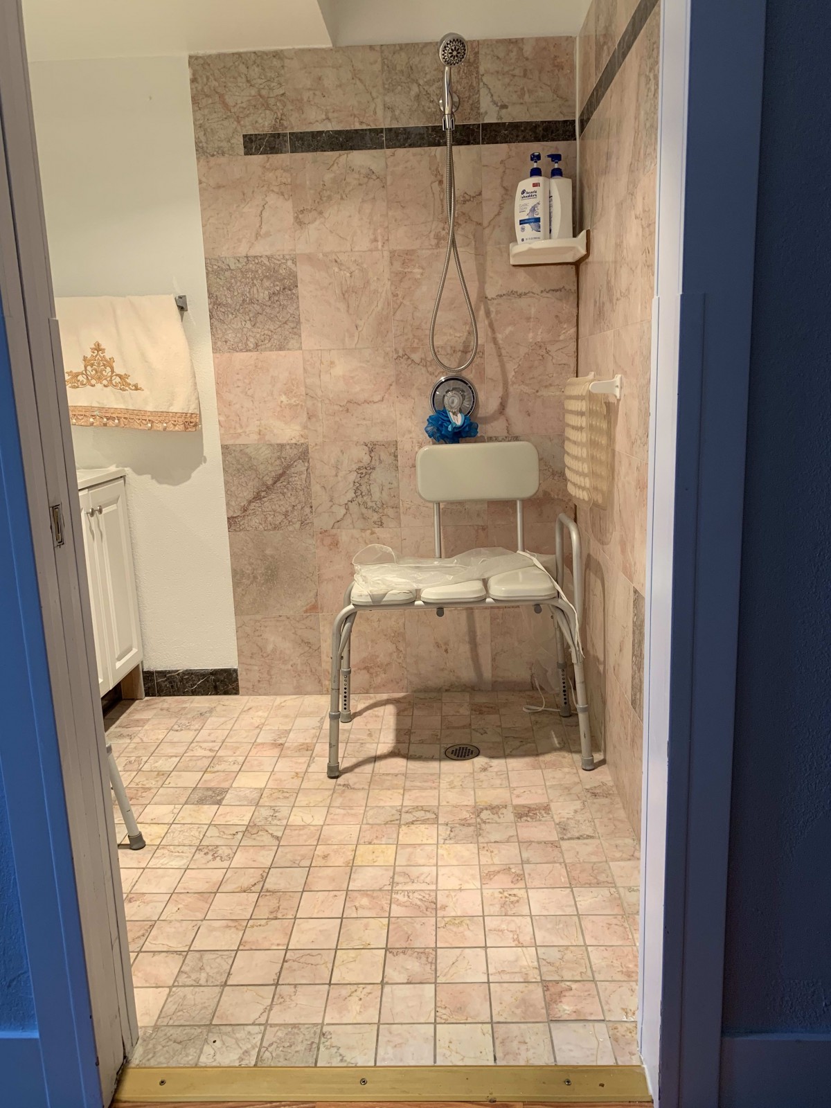 An accessible bathroom with a shower chair and grab bars.