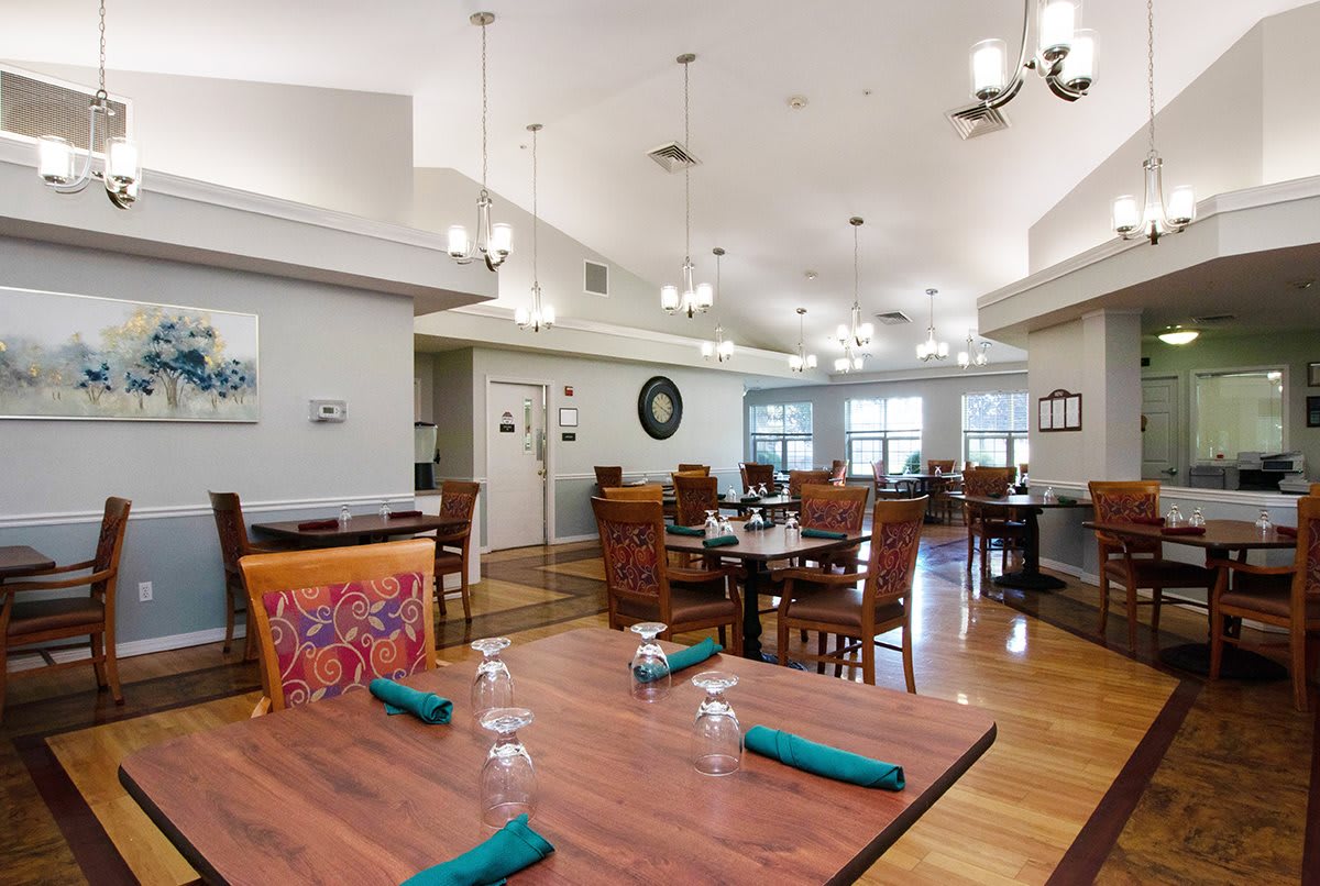 A cozy restaurant dining area with neatly arranged tables and chairs, featuring elegant lighting and decor.