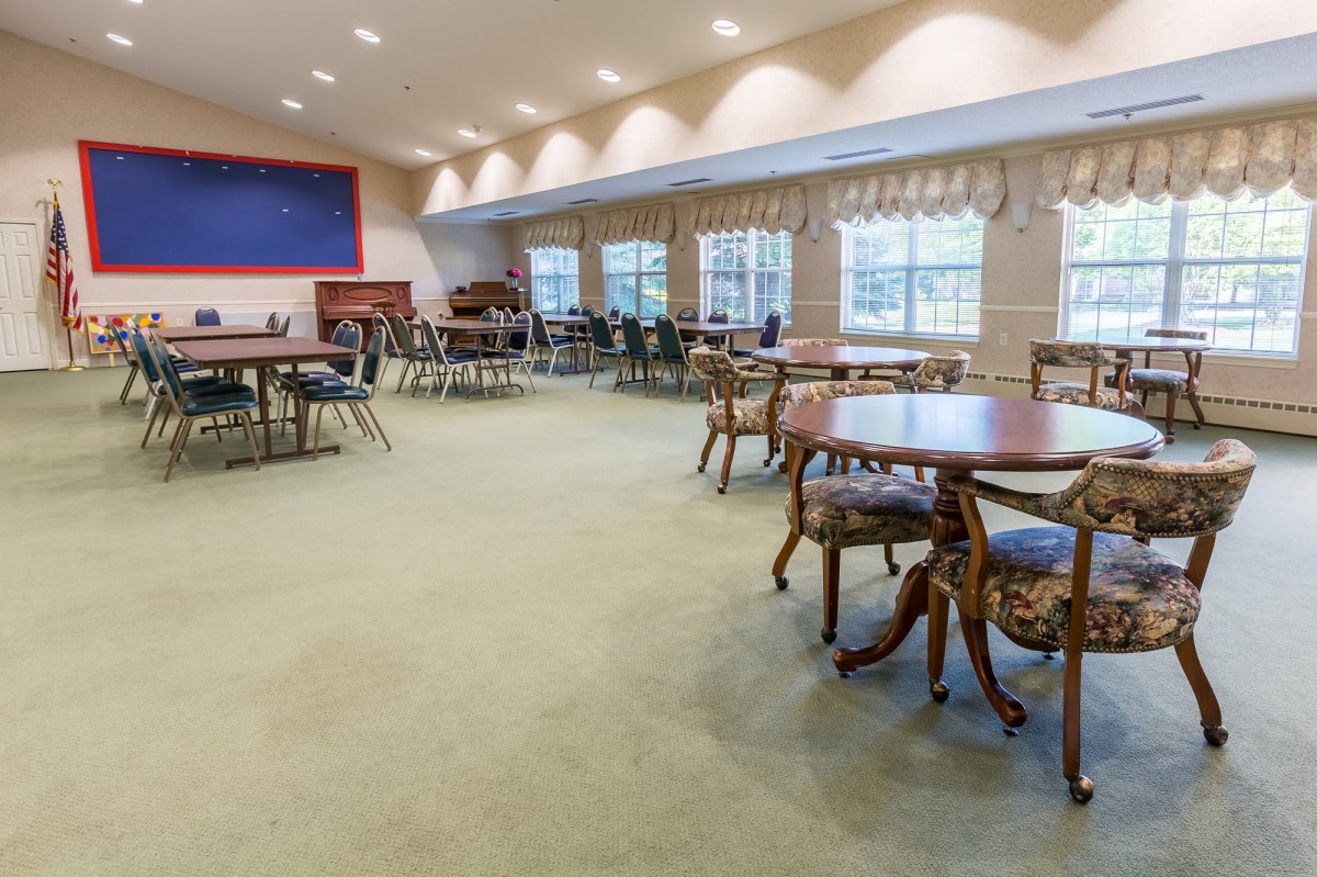 A spacious, well-lit room with multiple tables and chairs arranged for gatherings or events.