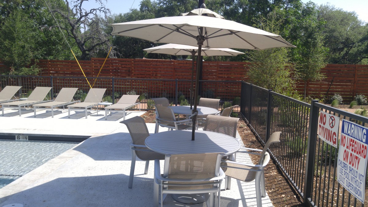 Outdoor patio area with tables, chairs, and umbrellas providing shade.