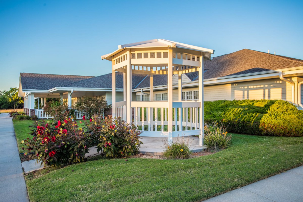 A charming gazebo stands amidst a well-maintained garden with vibrant flowers.