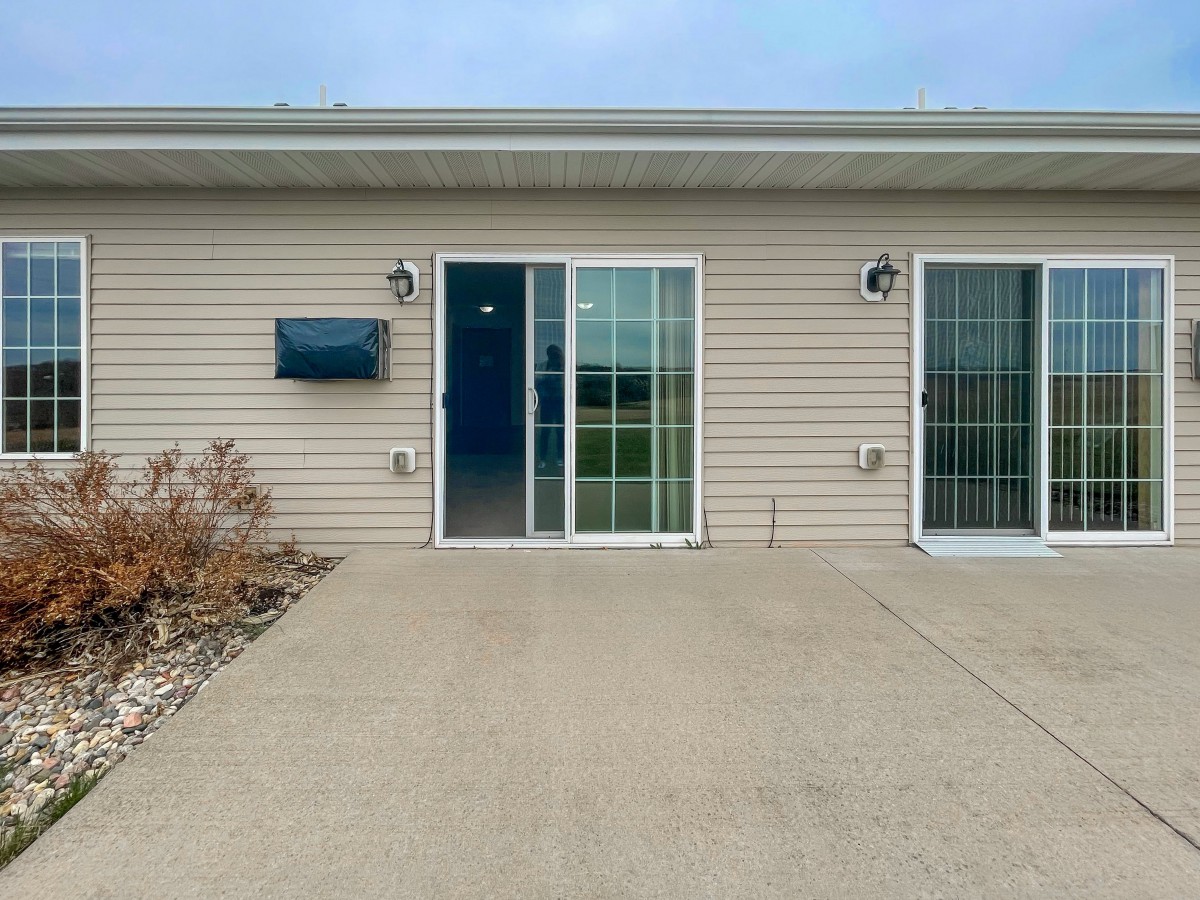 A house exterior with sliding doors leading to a concrete patio.