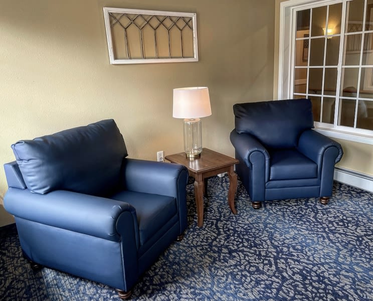 A cozy living room setting with two blue armchairs and a side table with a lamp.