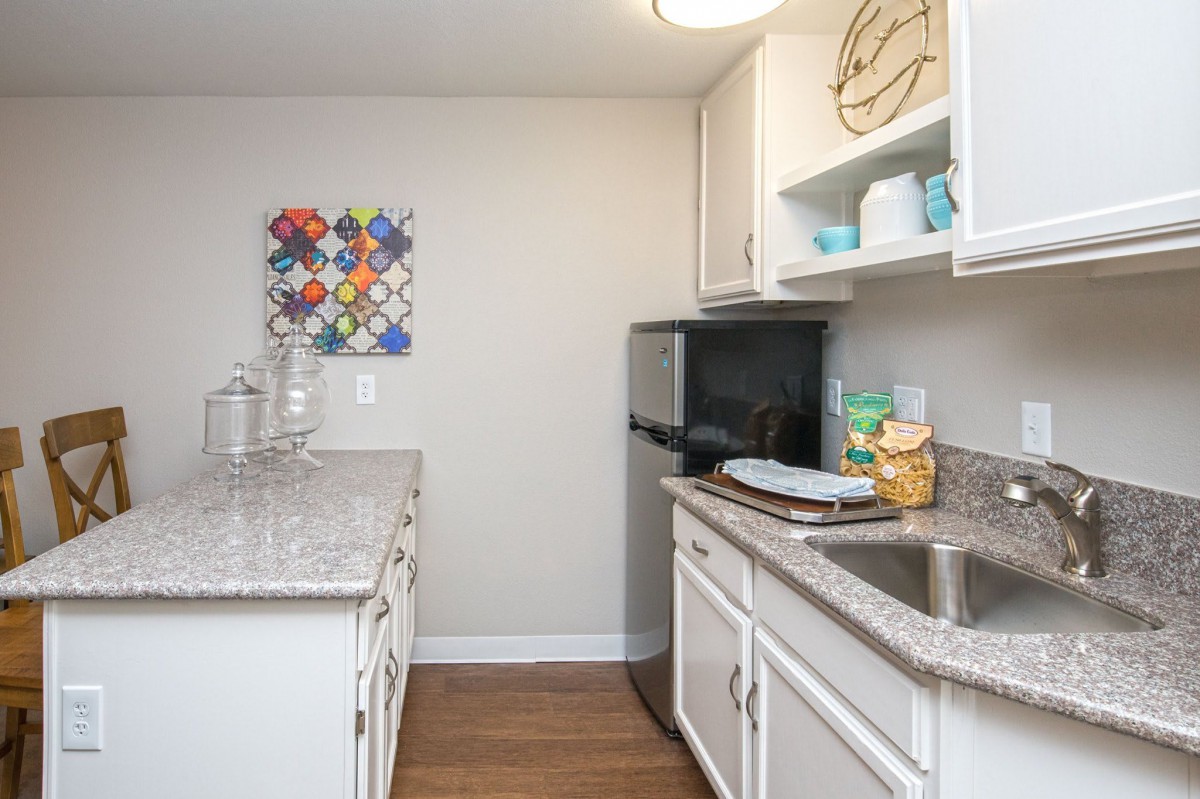 A compact kitchen area featuring white cabinets, a granite countertop, and small appliances.