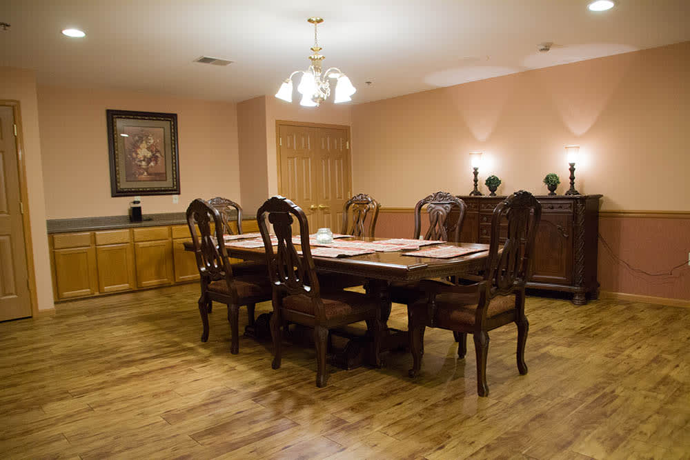 A cozy dining room with a wooden table set for a meal, featuring elegant chairs and a chandelier overhead.