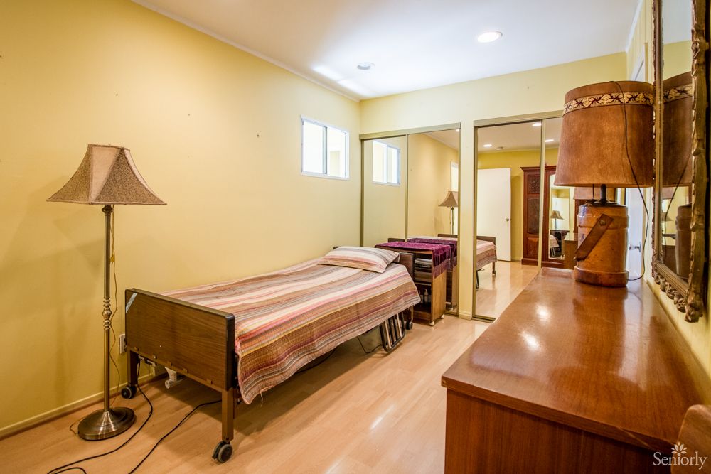 A cozy bedroom with yellow walls, featuring a single bed and wooden furniture.