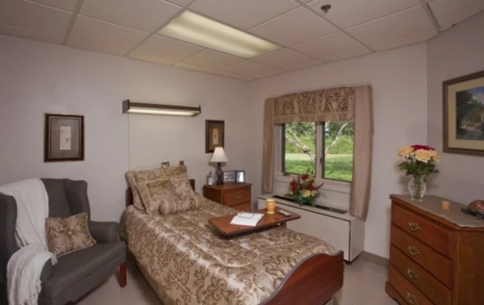 A comfortable hospital room with a single bed, bedside table, and window view.