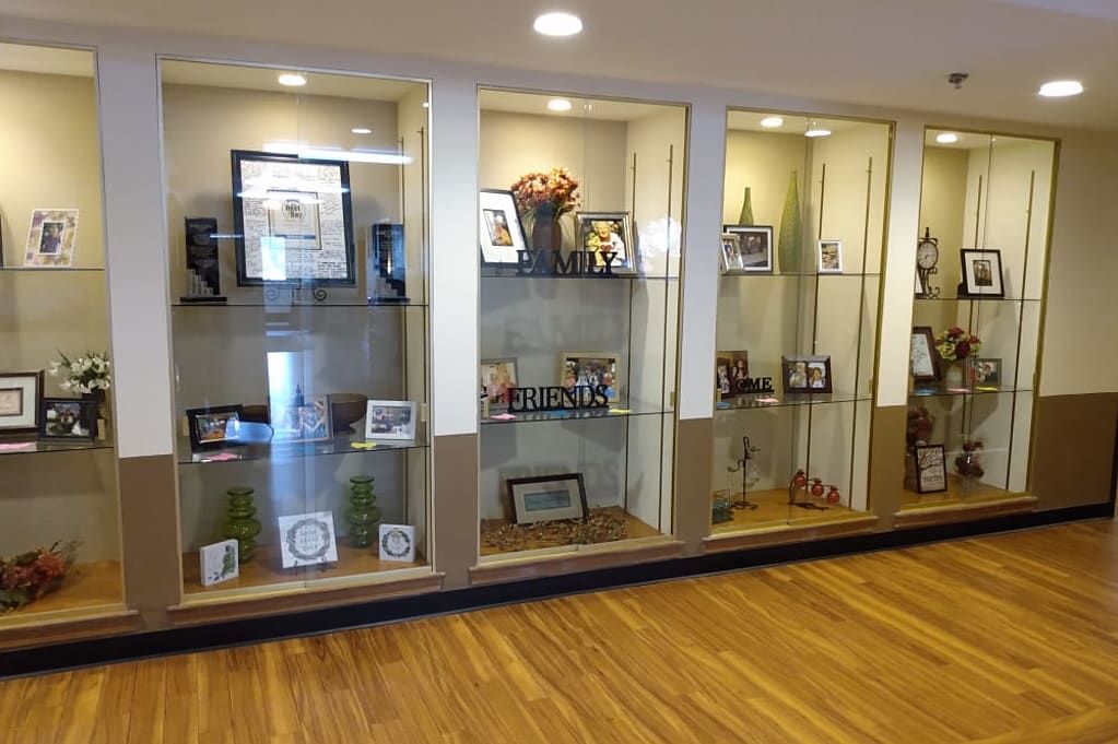 A well-lit display case showcasing various trophies, awards, and certificates in a room with wooden flooring.