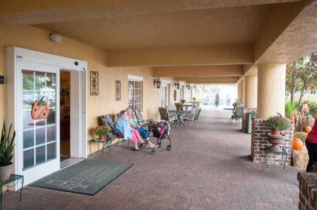 Elderly individuals sitting on a porch at a senior living facility.
