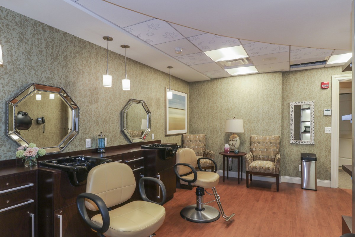 A cozy salon interior with styling chairs, mirrors, and a small waiting area.