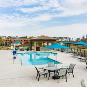 Outdoor swimming pool area with tables, chairs, and umbrellas.