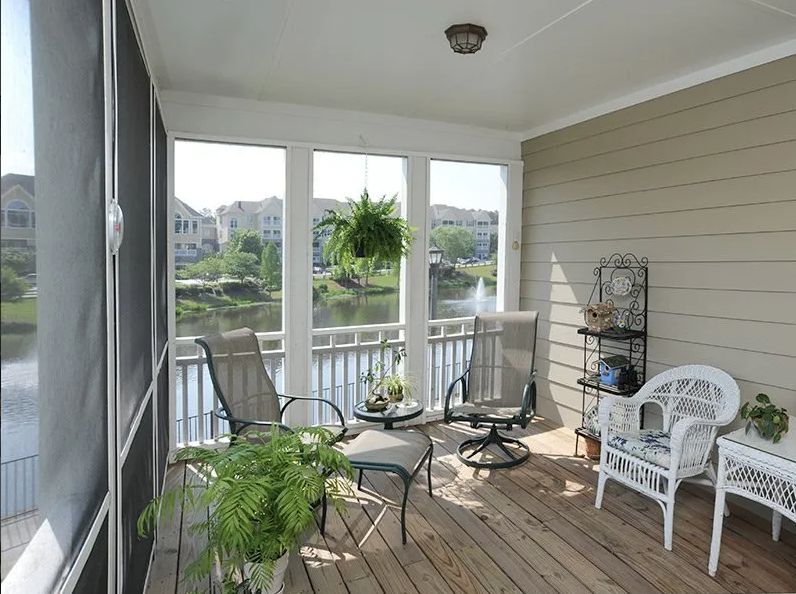 A cozy screened-in porch with comfortable seating and a view of the lake.