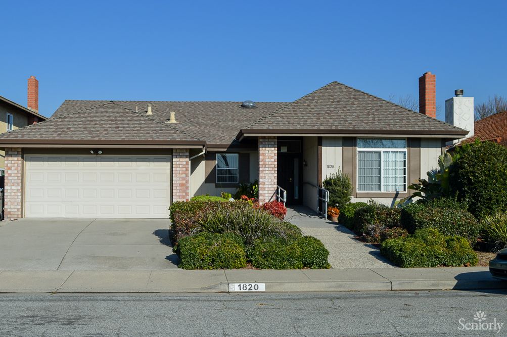 A suburban house with a well-maintained lawn and driveway under a clear blue sky.
