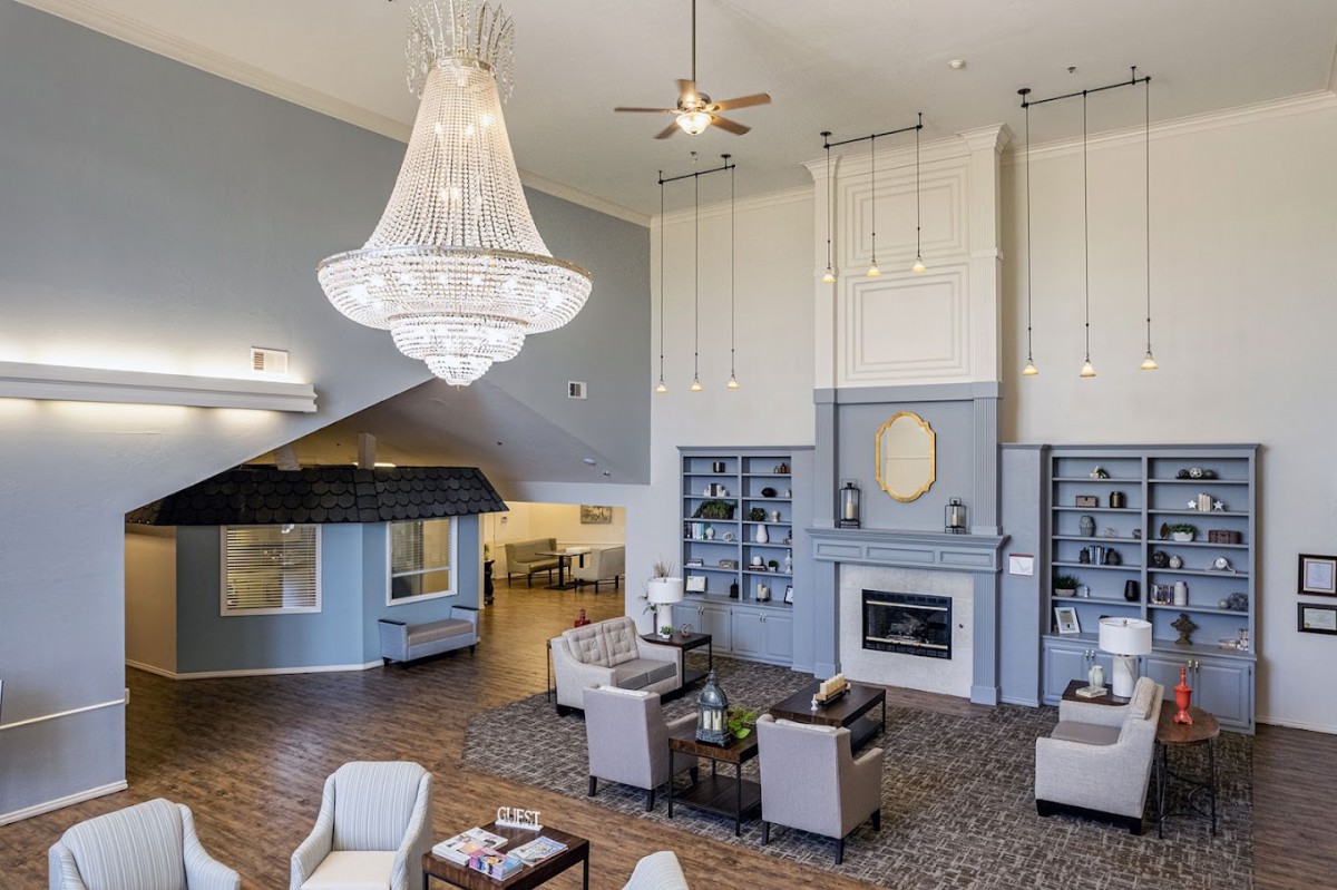 A spacious and elegantly designed living room featuring a grand chandelier, comfortable seating, and a fireplace.