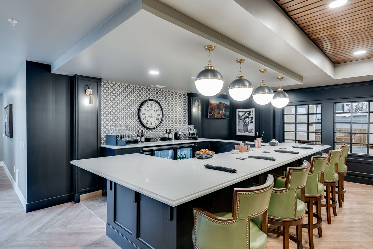 A modern home bar with stylish pendant lighting and a spacious countertop.