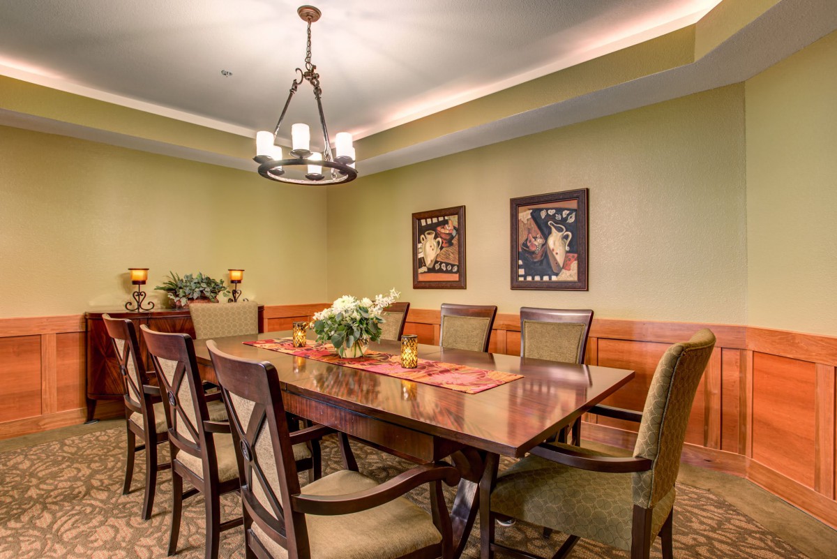 A well-decorated dining room with a wooden table, upholstered chairs, and elegant lighting.