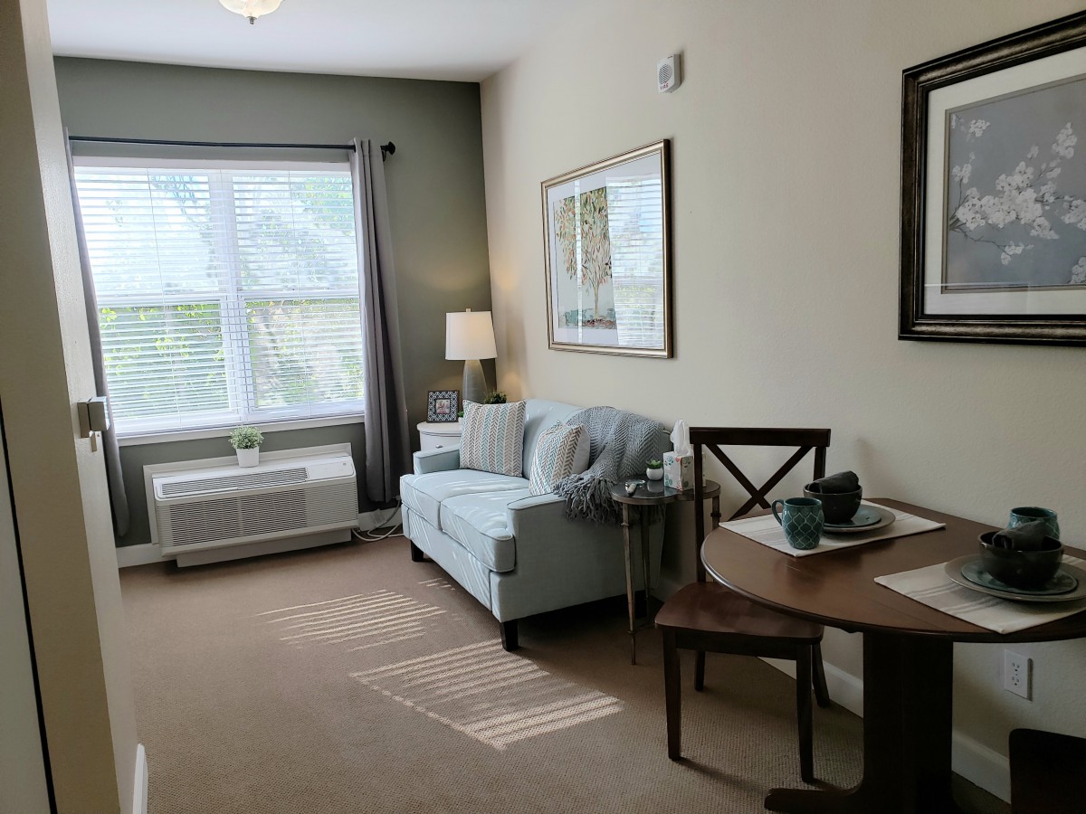 A cozy living room with a sofa, table, and large window.