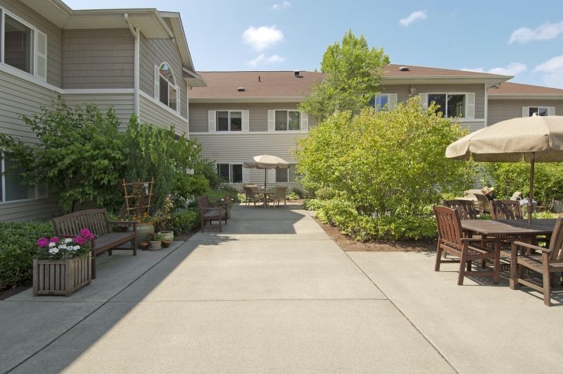 A courtyard with outdoor seating and lush greenery on a sunny day.