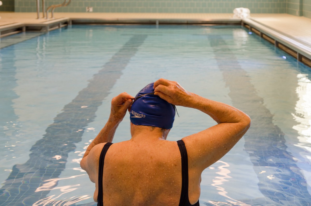 A swimmer adjusts their swim cap before starting a session in the pool.