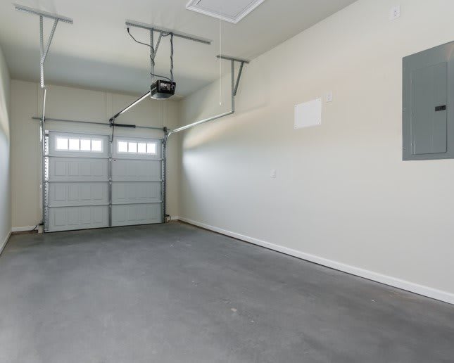 An empty and clean garage with a concrete floor and closed garage door.