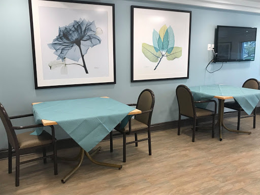 A cozy dining area featuring blue tablecloths, modern chairs, and artistic wall decor.