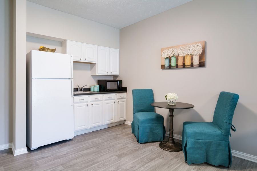 A compact kitchen area with white cabinetry and teal-accented seating.