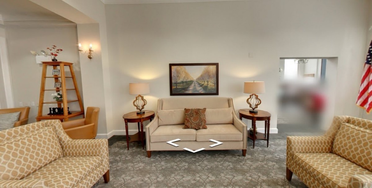A cozy living room with a beige sofa, side tables with lamps, and a framed artwork above.