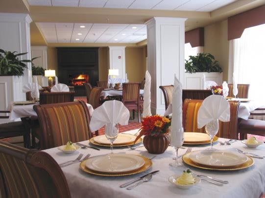An elegantly set table in a restaurant dining area, featuring folded napkins, plates, and cutlery.