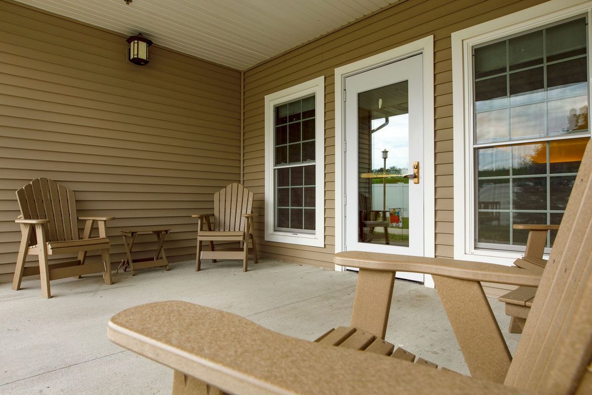 A cozy porch with wooden chairs and a glass door entry.