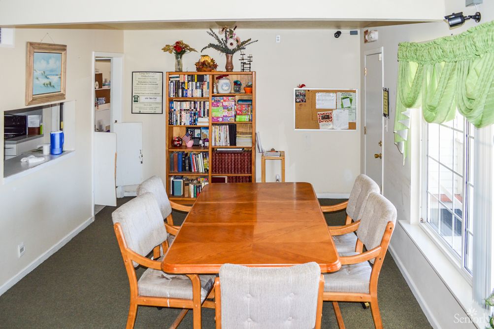 A cozy dining room with a wooden table and chairs, complemented by a bookshelf in the background.