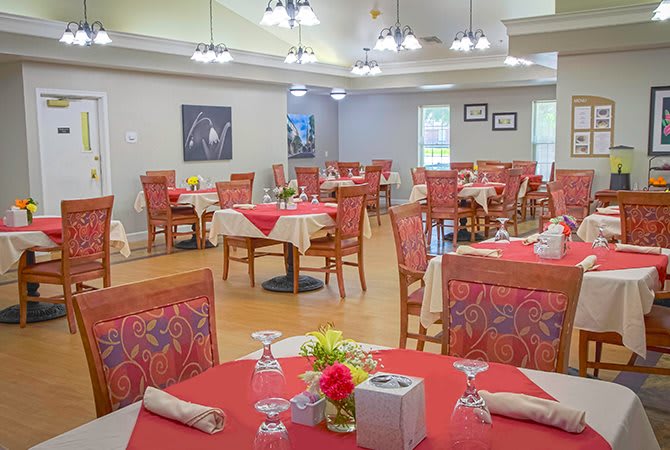 A well-arranged dining area featuring tables with red tablecloths and neatly set place settings.