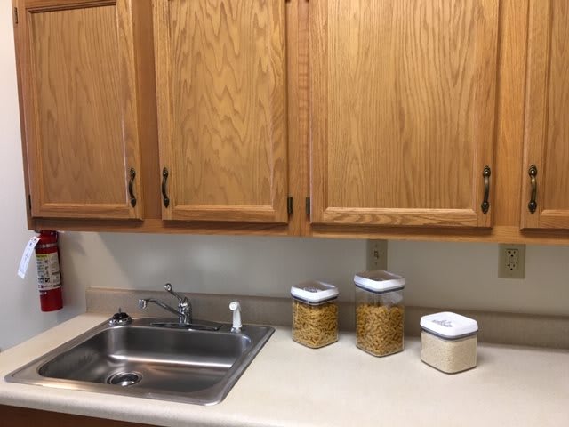 A kitchen scene with wooden cabinets, a sink, and storage containers on the countertop.