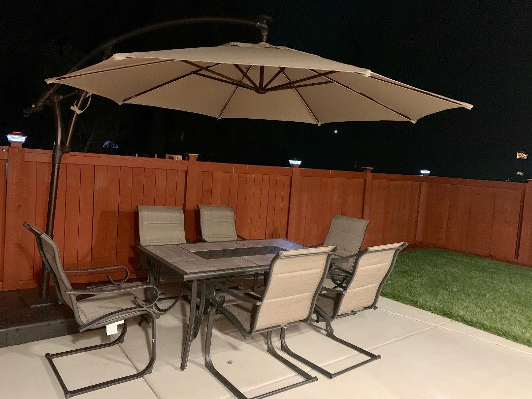 Outdoor patio set with a table, chairs, and large umbrella at night.