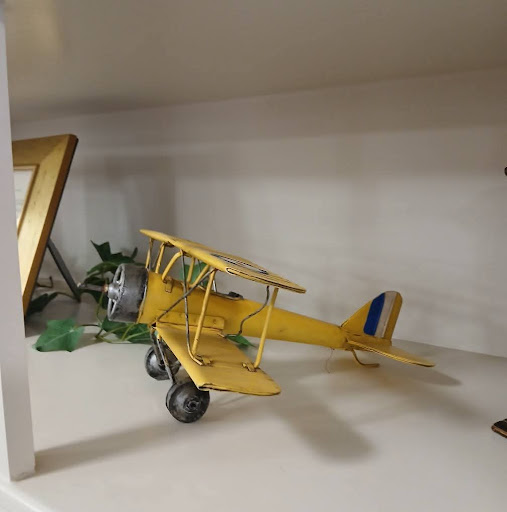 A vibrant yellow model biplane displayed on a shelf.