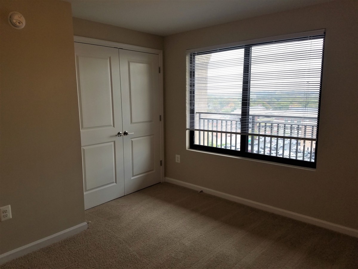 An empty bedroom with a window and a closet.