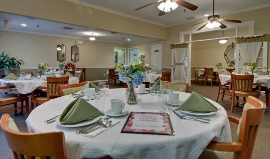 A well-arranged dining room table with neatly folded green napkins and a floral centerpiece.