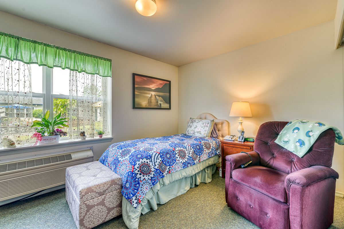 A cozy bedroom with a single bed, armchair, and a window bringing in natural light.