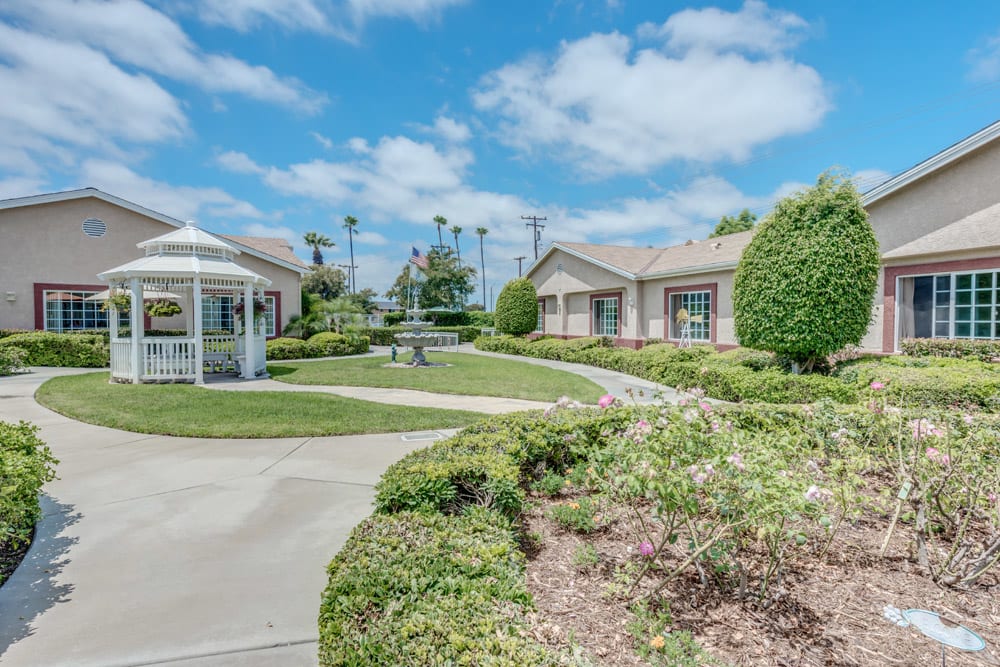 A beautiful garden area with a gazebo and fountain surrounded by buildings under a clear blue sky.