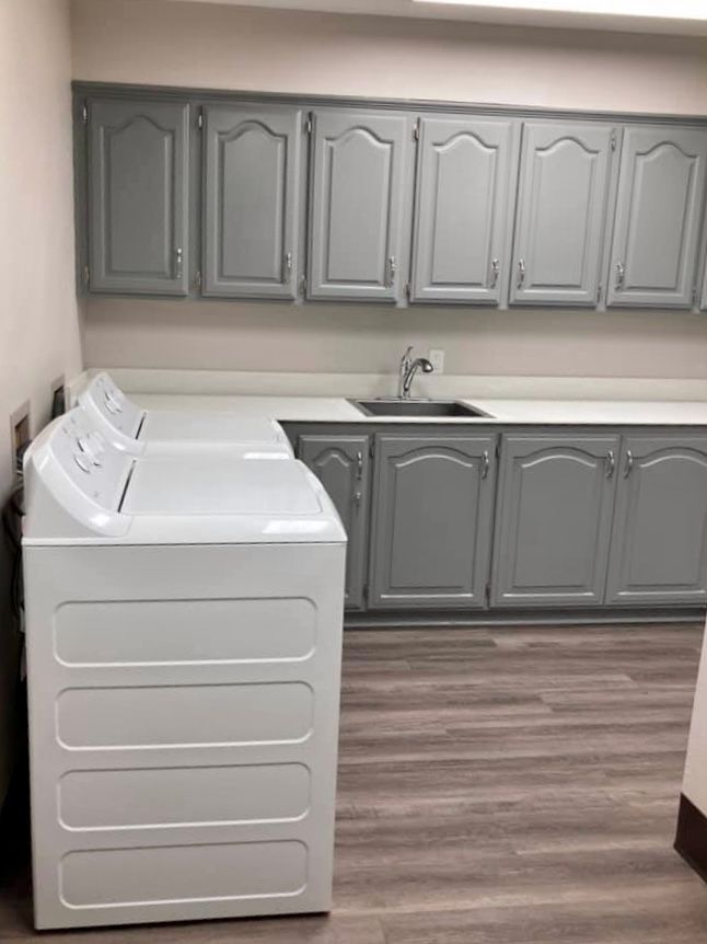 A modern laundry room with a washer, dryer, and ample cabinet space.