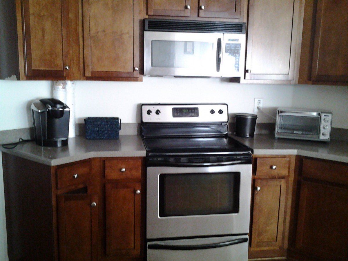 A modern kitchen with wooden cabinets, a stainless steel stove, and a microwave.