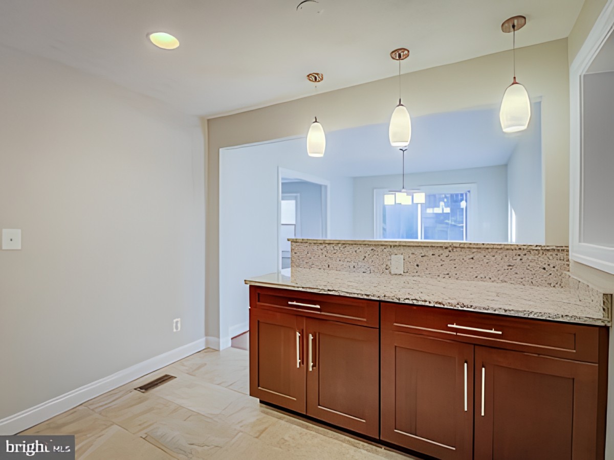 A modern kitchen with wooden cabinets and pendant lighting.