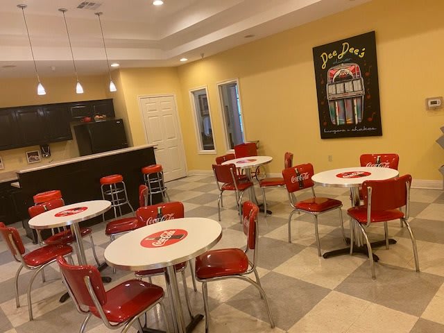A retro-style diner with red chairs and white tables, featuring vintage decor.
