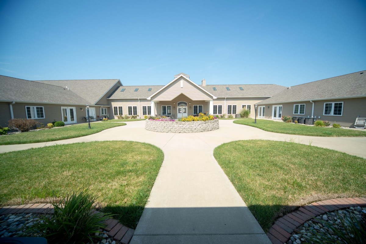 A symmetrical building with a central pathway and landscaped grounds under a clear blue sky.