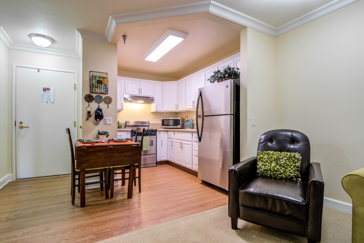 A cozy kitchen with a dining area featuring wooden floors and a modern refrigerator.
