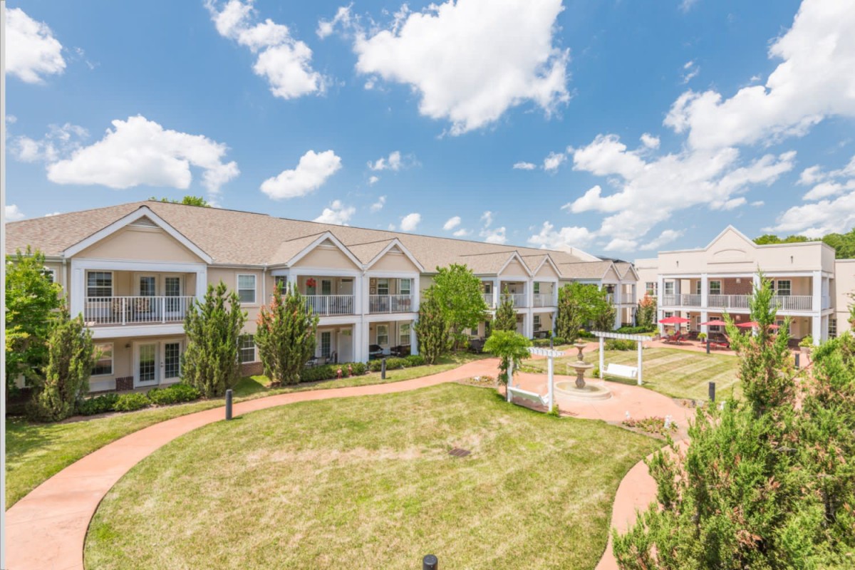 A sunny day view of a residential apartment complex with well-maintained landscaping.